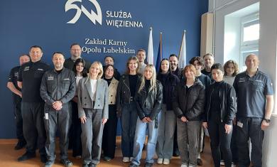 Zdjęcie przedstawia grupę studentów oraz funkcjonariuszy w mundurach na granatowym tle widać napis Służba Więzienna oraz Zakład Karny w Opolu Lubelskiem.