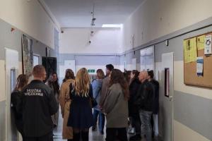 Grupa osób rozmawiających z umundurowanymi funkcjonariuszami Służby
